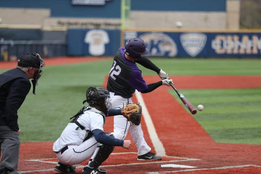 Hitter wearing number 12 making contact with a pitch