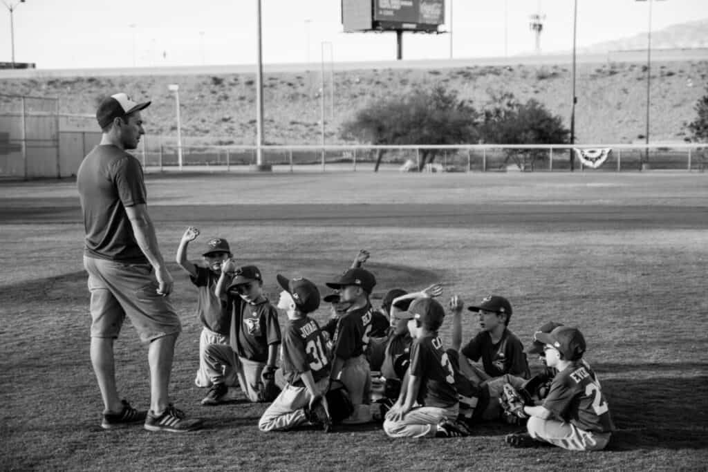 Every player on a youth baseball team taking a knee while the coach speaks