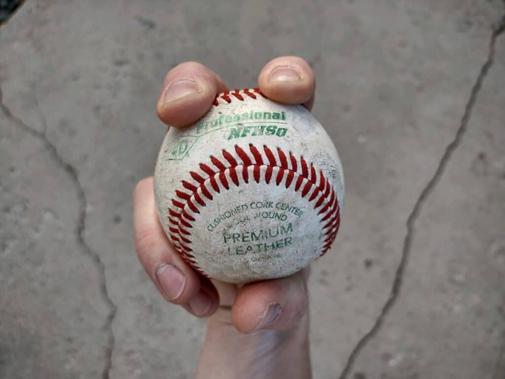 Bottom view of a hand demonstrating how to grip a sinker with two fingers over the horseshoe-shaped seams of the baseball