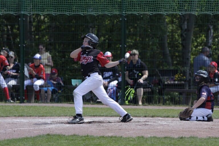 A youth baseball player finishing a swing and preparing to run to first base