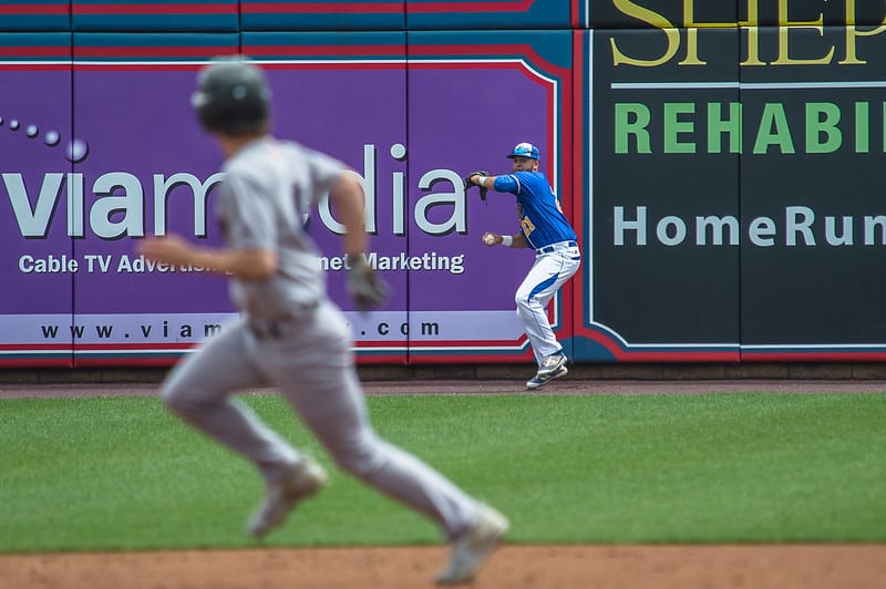 Baserunner and center fielder looking at each other while the center fielder winds up to throw the ball