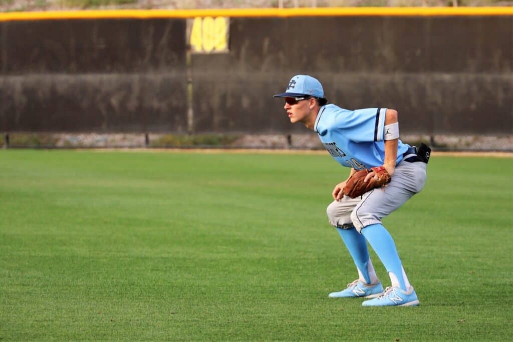 A right fielder in a light blue uniform gets into the ready position