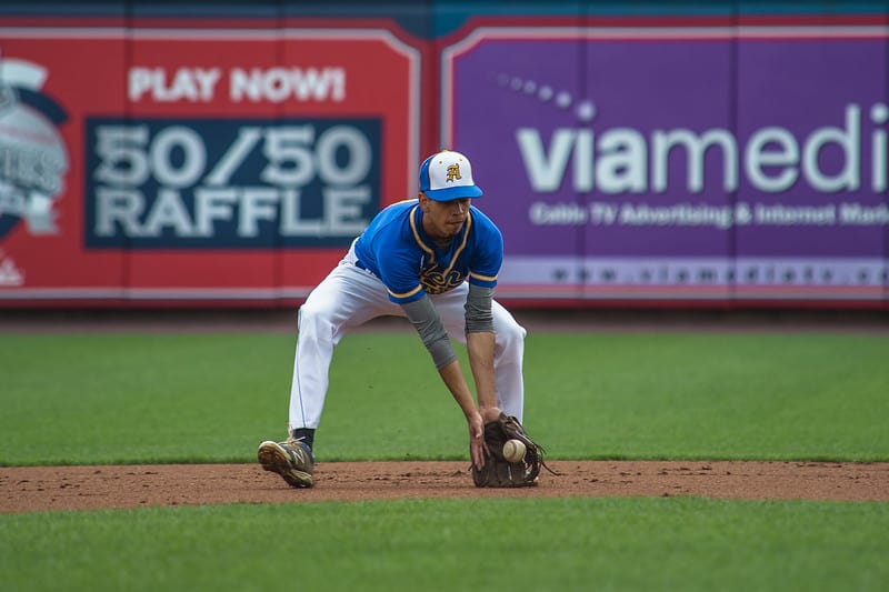 Shortstop in blue uniform fielding a ground ball