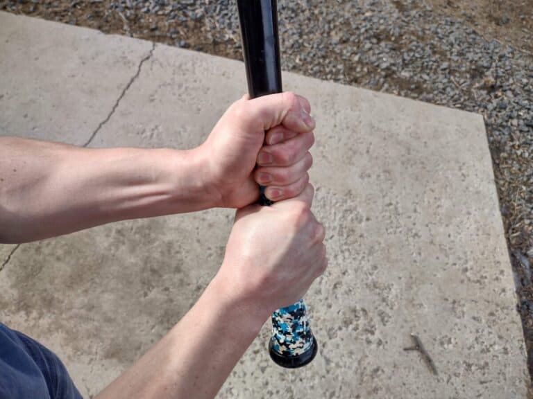 Two hands holding a baseball bat demonstrating how to choke up on a bat