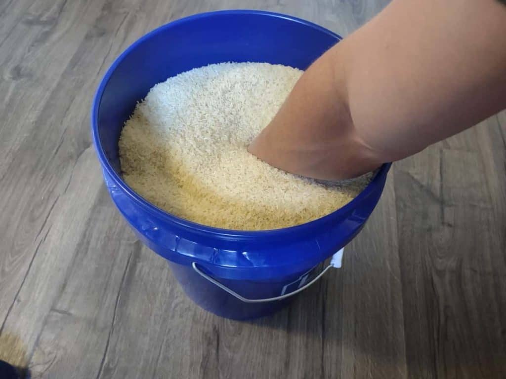 Dipping hand into a five-gallon bucket of rice to perform a move called "Deep Grabs"