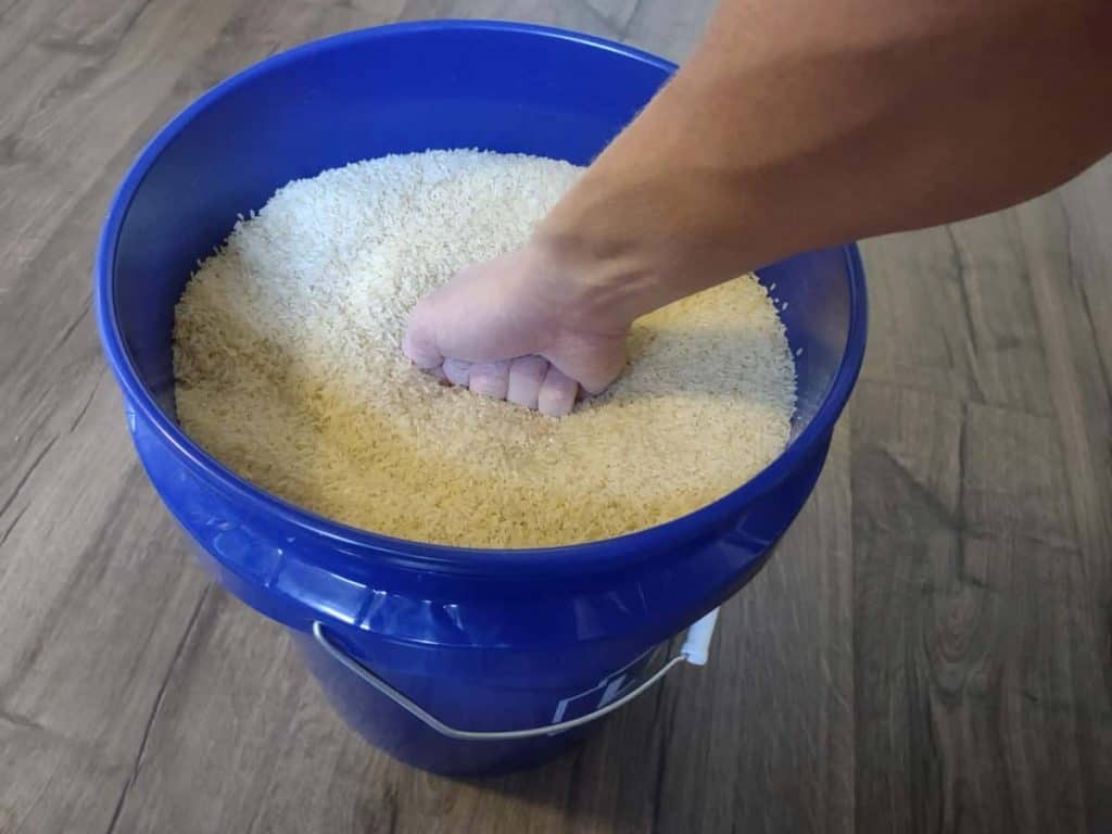 Making a fist over a five-gallon bucket filled with rice