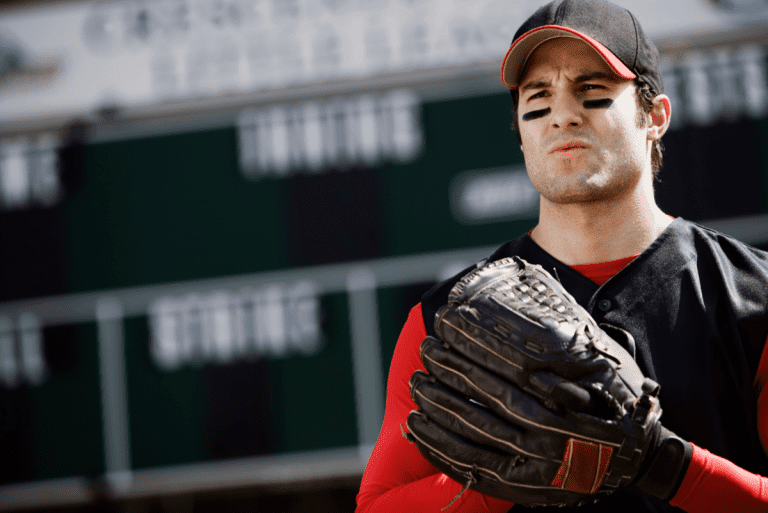 A baseball player in a red and black uniform wearing black eyeblack under both eyes