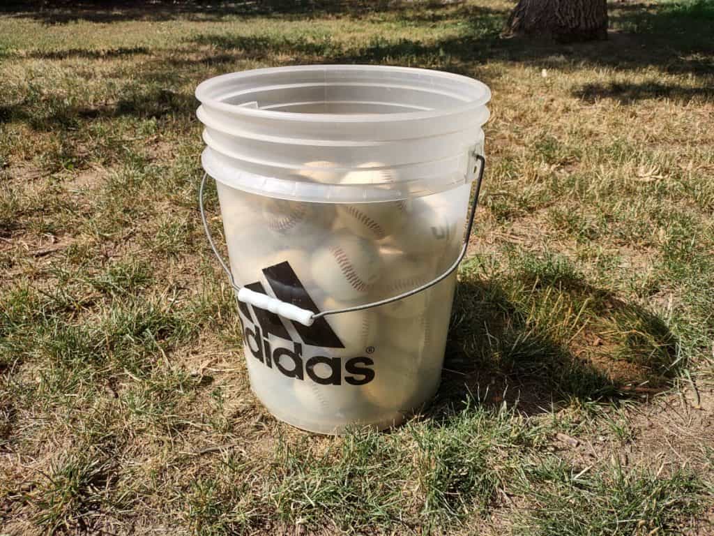 A 5-gallon plastic adidas bucket filled three-quarter with baseballs