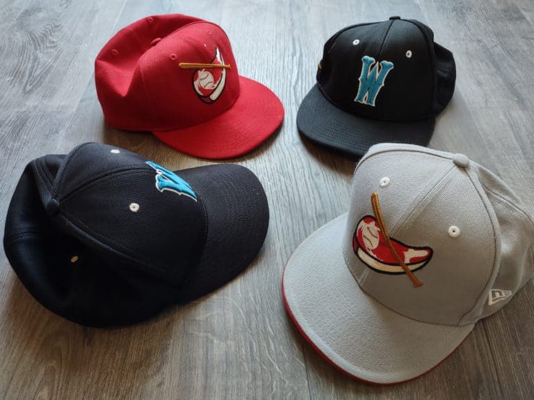 Four baseball hats laying on a wood floor