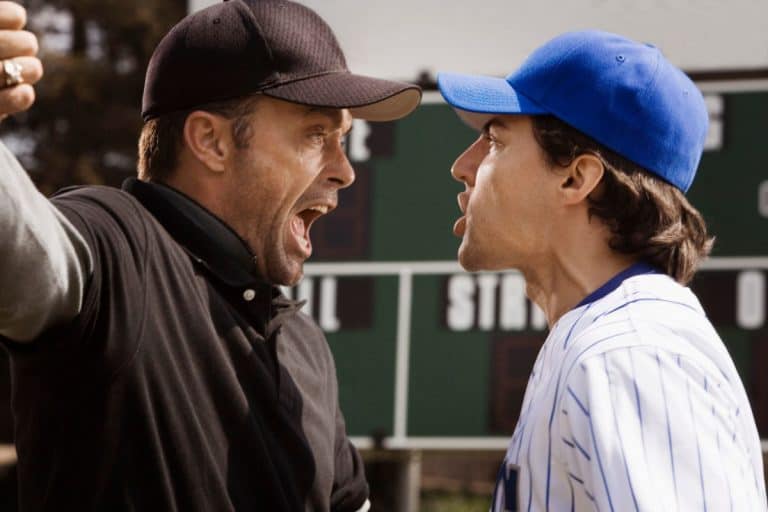 Baseball player in a blue pinstripe uniform arguing with an umpire