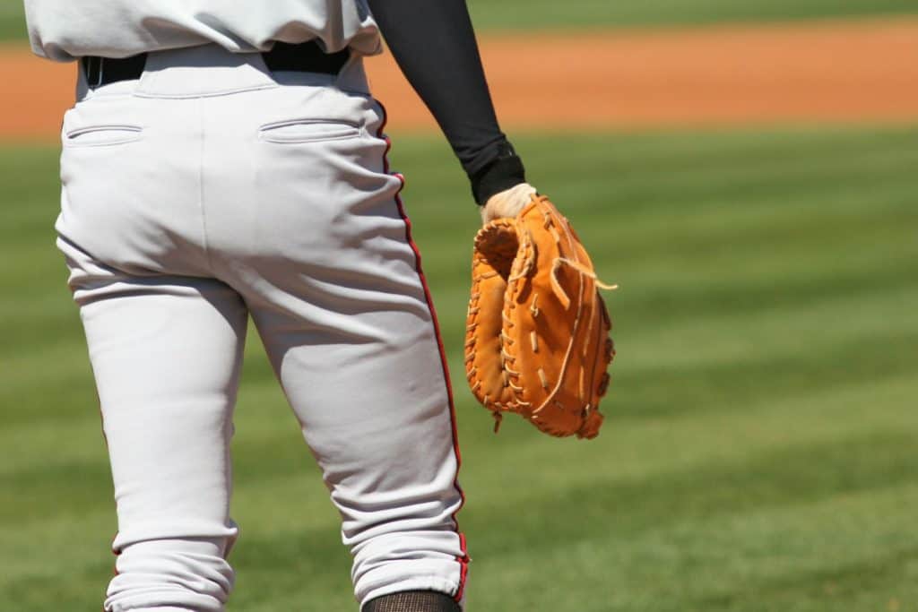 Waist-down closeup of an outfielder in a gray uniform and wearing long sleeves