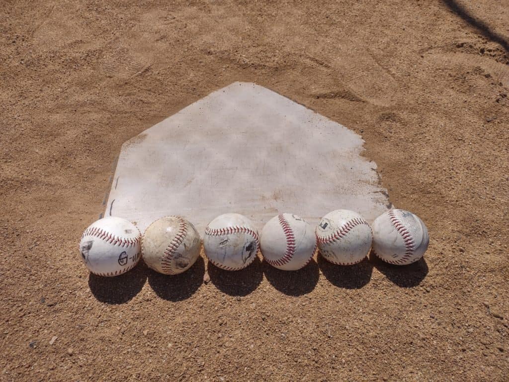 Backside view of home plate being measured as six baseballs wide