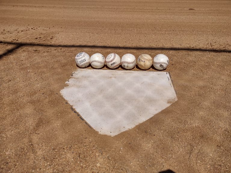 Front view of home plate being measured as six baseballs wide