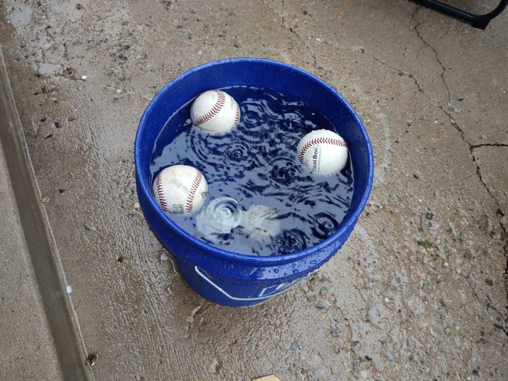 Used leather baseball sinks after a brand new leather baseball in a 5-gallon bucket of water