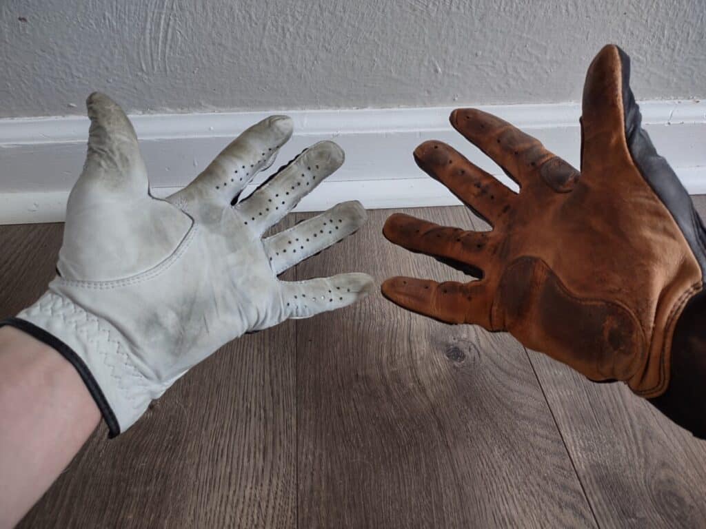Palm view of a left hand wearing a golf glove and the right hand wearing a batting glove
