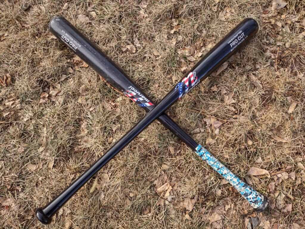 Two Marucci USA Professional Cut wood bats in the shape of an X and laying on the grass