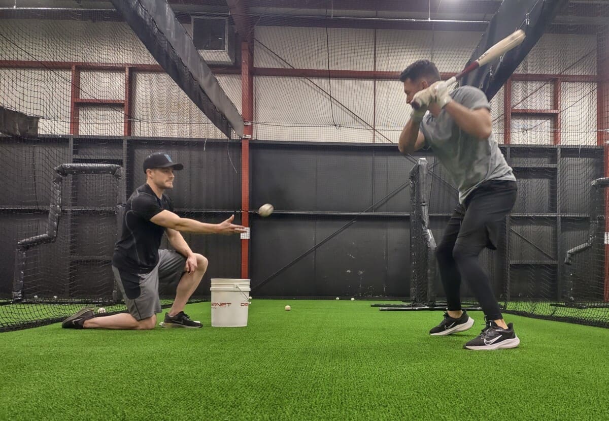 Pitcher throwing soft toss to hitter with wood bat