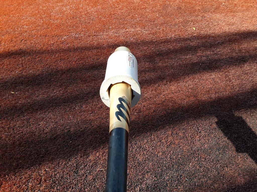Wood Marucci baseball bat with black handle and a batting weight attached to the barrel