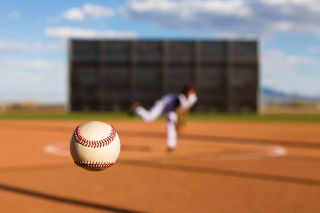 Closeup of a baseball pitch that looks like a knuckleball with a blurry pitcher in the background