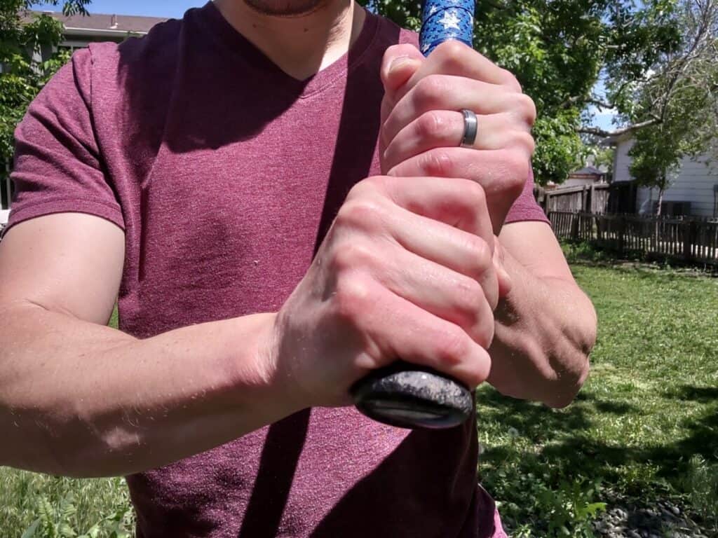 Demonstrating how the bottom hand makes contact with the knob of the baseball bat