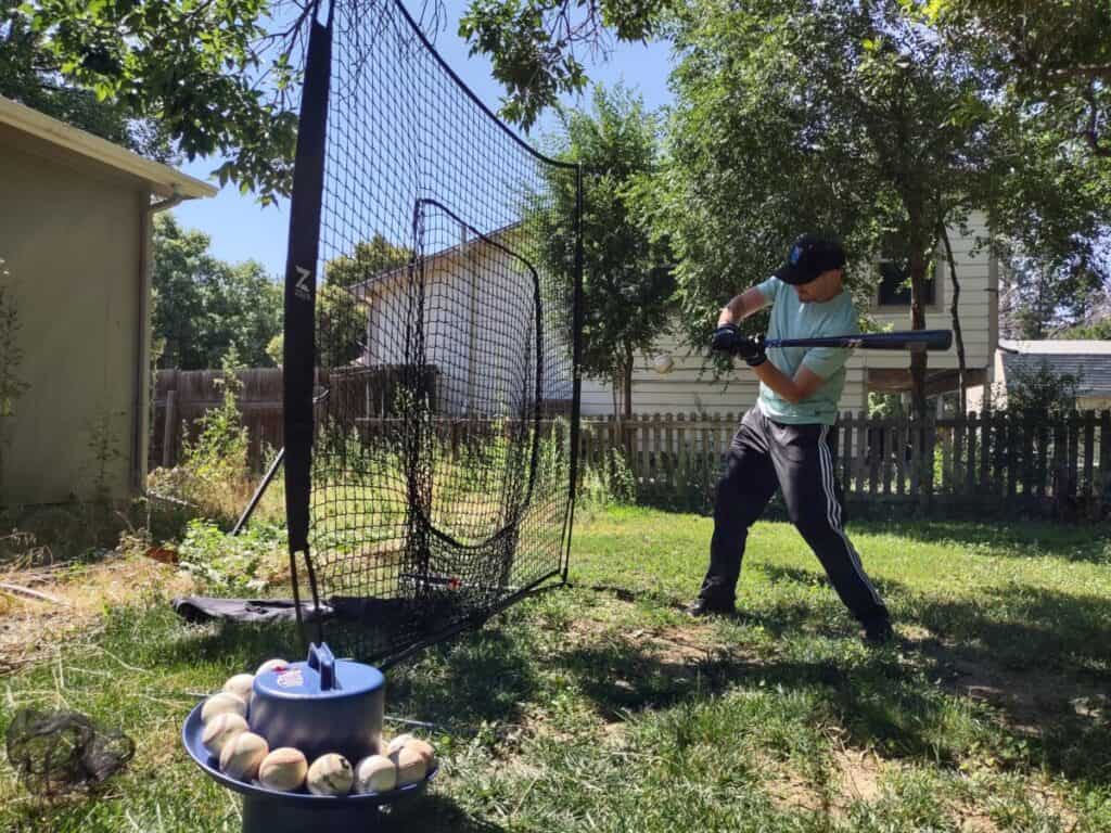 Steve Nelson in a backyard swinging at a soft toss pitch from a Jugs Soft Toss machine