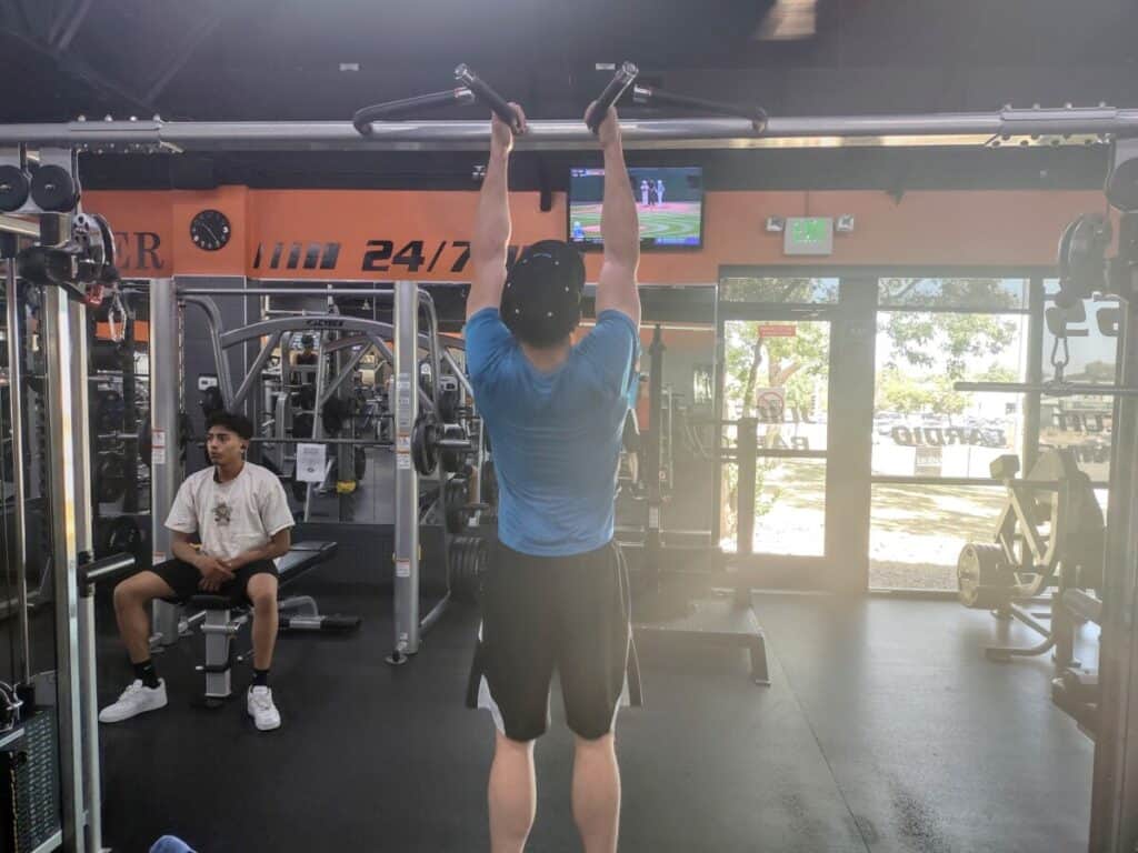 Starting position of the neutral grip pull-up exercise. Player is hanging from a pullup bar with his arms extended and his palms are facing each other.
